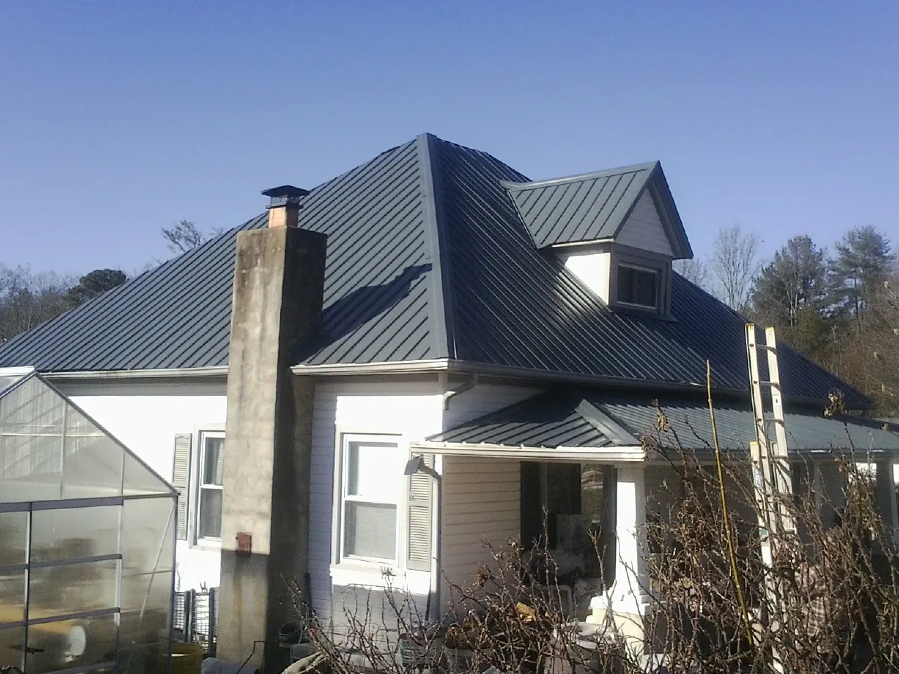 Dark blue standing seam metal roof on a white farmhouse with dormer — Slate & Tile Roof Repair by Roofing Brothers in Eatontown