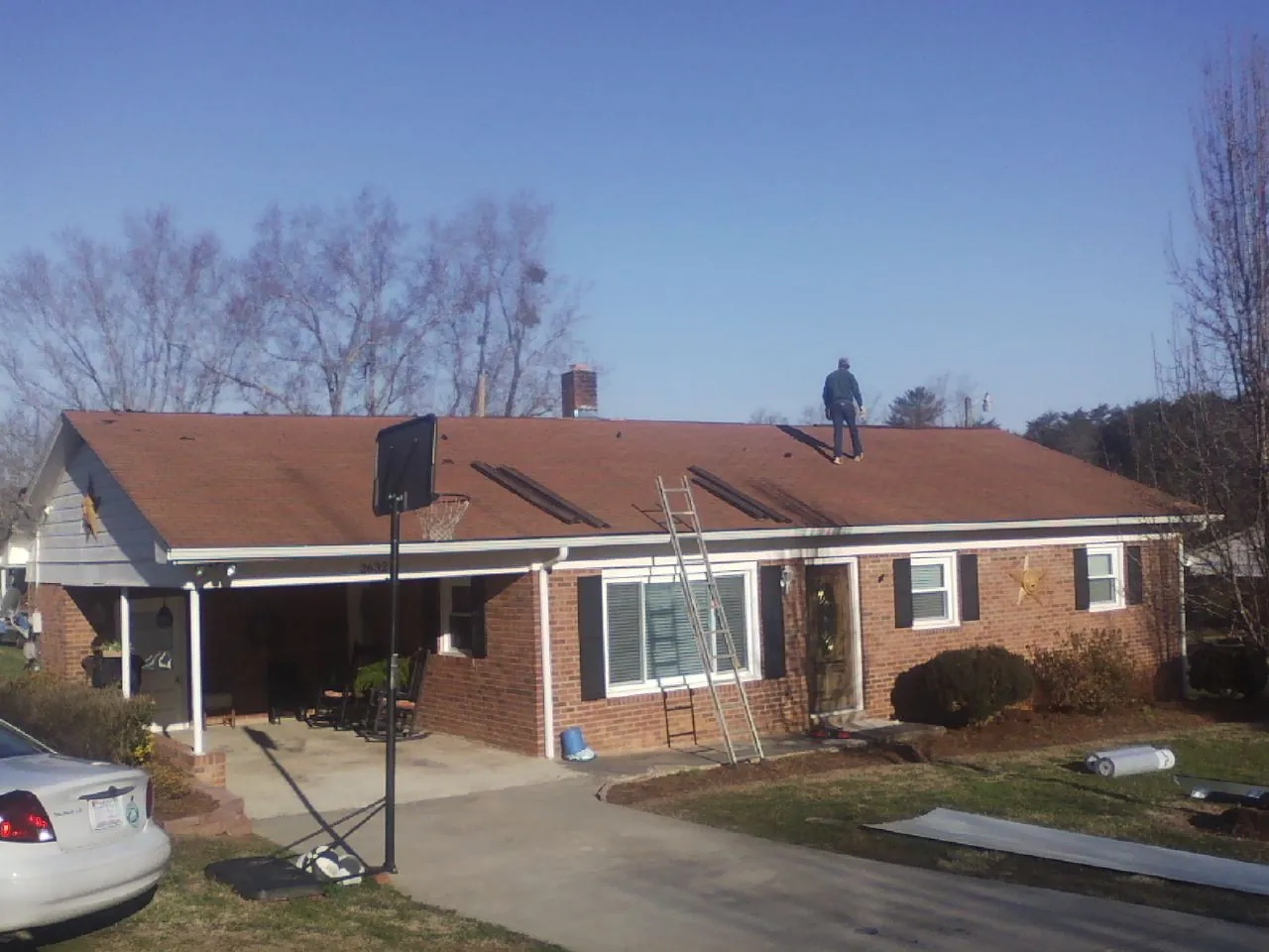Roofer stripping a shingle roof on a brick ranch before metal panels in Eatontown