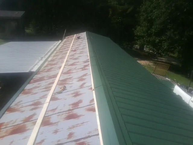 Old rusted panels beside newly installed green metal roofing — Wind Damage Roof Repair by Roofing Brothers in Eatontown