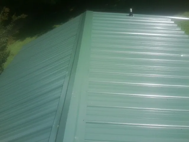 New green metal panels meeting at the ridge of a roof — Flat Roof Repair work by our crew in Eatontown