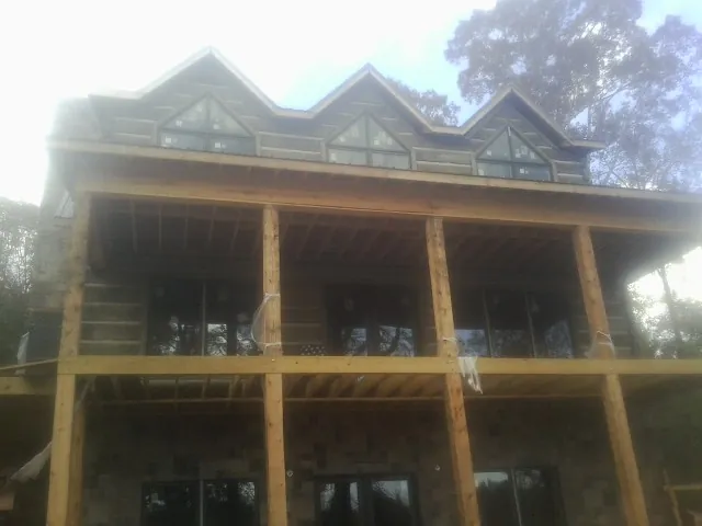 Dormers and porch framing on a large log home under construction — Roof Coating work by our crew in Eatontown