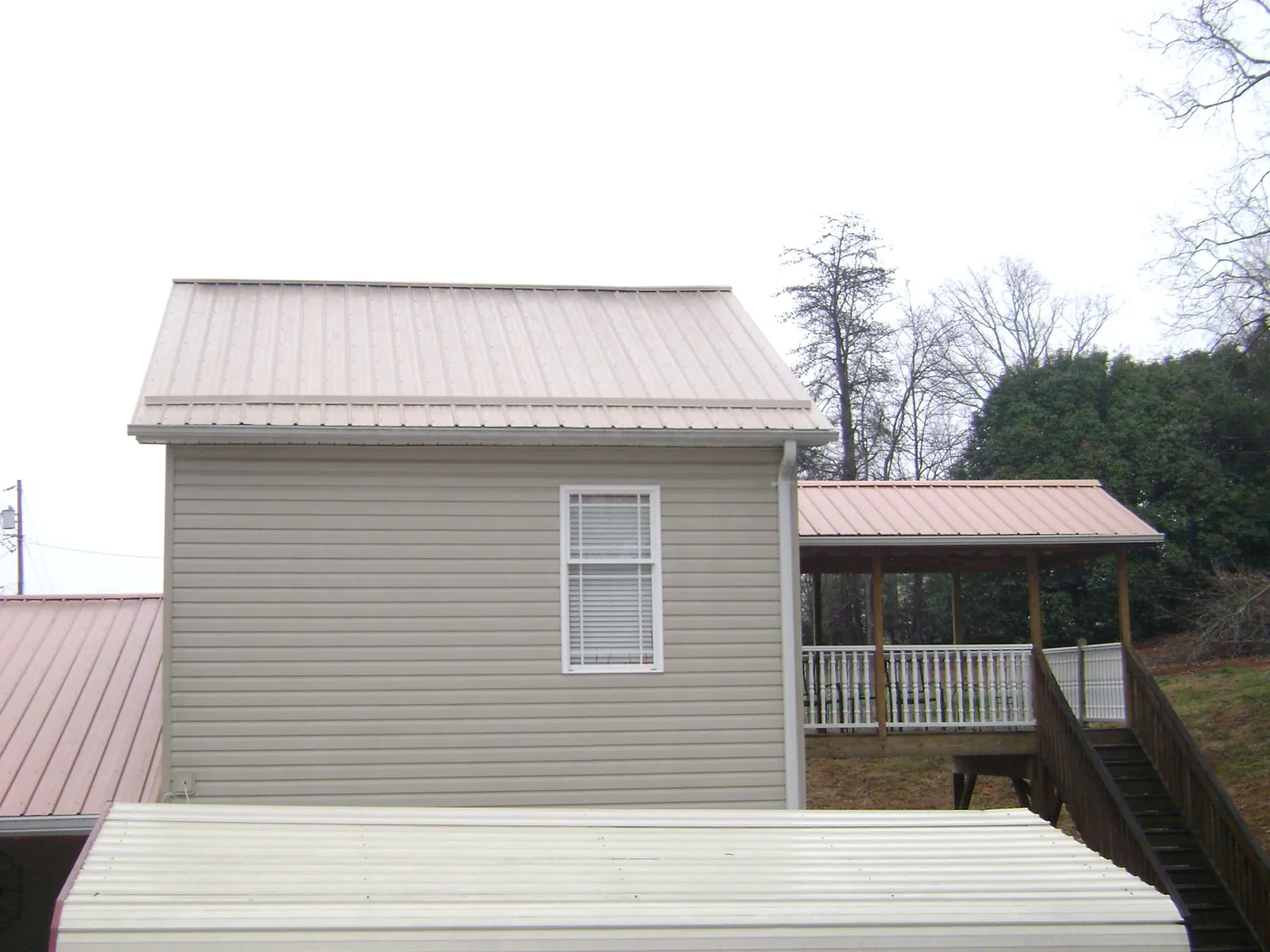 Tan metal roofs on a two story addition and attached porch, from a Roof Replacement job in Eatontown