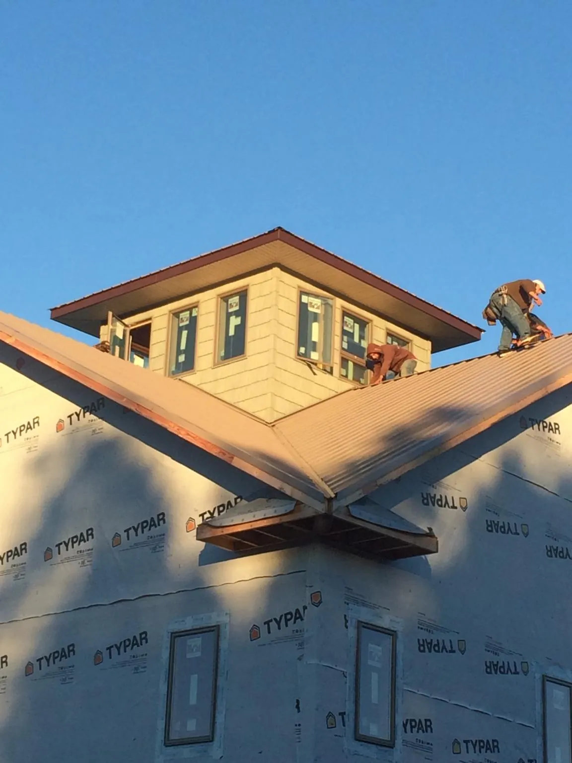 Roofers working around a rooftop cupola on a new metal roof at sunset — Roof Waterproofing in Eatontown by Roofing Brothers